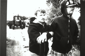 Henningson leads Hanson away from the protest after Hanson threatened to lie down in the driveway to block the removal of auctioned farm equipment.